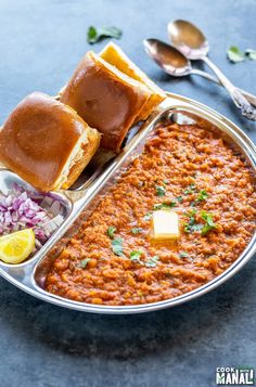 a metal tray filled with food next to silver spoons