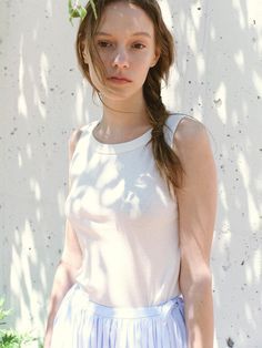 a young woman standing in front of a white wall