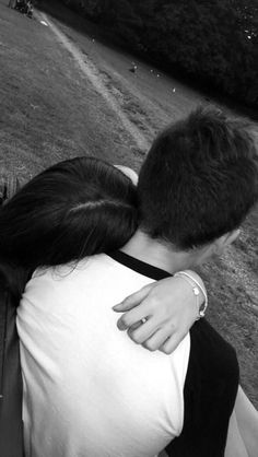 a man and woman hugging each other in the park