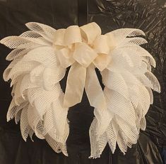 a white wreath is hanging on a black sheeted wall and it's made out of mesh