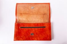 This beautiful clutch handbag is made out of real leather, and was likely made inbetween the 1960s and 1980s.  It's main color is auburn or a reddish brown tone. There is a zipper pocket, and the bag can be closed with a hidden single button. On the front there a subtle pattern of stitches and a thick line. The condition is good, with a few signs of age and use (such as a few crinkles and usual age discolorations). Please see pictures for details. Dimensions: ca. 15,5 cm heigth, ca. 28 cm width, ca. 180 g weight. Vintage Brown Satchel Clutch, Brown Leather Clutch With Snap Closure, Vintage Leather Travel Clutch, Red Vintage Leather Wallets, Vintage Leather Clutch For Everyday Use, Retro Brown Rectangular Clutch, Red Vintage Clutch For Daily Use, Vintage Leather Clutch Wallet, Vintage Brown Leather Clutch