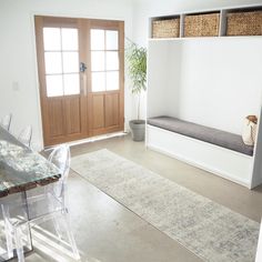 a room with a table, chairs and a bench on the floor in front of a door