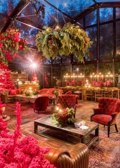 a living room filled with lots of red furniture and flowers on the table in front of it