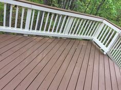 a wooden deck with white railings in the woods