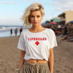 Introducing our Lifeguard Women's Crop Tee in a striking red on a crisp white shirt - a dynamic blend of iconic style and beach-ready charm that captures the essence of coastal life. Designed with a trendy cropped cut, this tee features the classic lifeguard logo, invoking a sense of safety and adventure. Crafted from soft and breathable materials, it offers both comfort and a touch of nostalgia. Whether you're hitting the beach, soaking up the sun, or simply embracing the carefree spirit of the shore, our Lifeguard Women's Crop Tee invites you to channel your inner beach babe and relish in the ocean's allure. Elevate your beach fashion and let your outfit reflect your love for the sea and its endless possibilities. .: 100% combed cotton (fiber content may vary for different colors) .: Med Red Short Sleeve Crop Top For Summer, Beach Crop Top With Short Sleeves, Short Sleeve Crop Top For Beach, Short Sleeve Crop Top For Beach Season, Casual Crew Neck Crop Top For Beach Season, Beach Season Beachwear Crop Top With Short Sleeves, Summer Beach Crew Neck Crop Top, Beach Season Short Sleeve Crop Top, Summer Beach Crop Top With Crew Neck