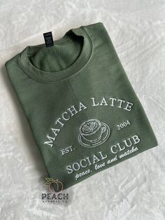 The "Matcha Latte Social Club" is a super cute trending shirt! Made in USA with embroidered stitching. Material: 50/50 Cotton, Poly Blend Slight Stretch Elastic/Knit Trim Fit: All shirt styles are Unisex Care: Machine wash cold. Tumble Dry Low Casual Short Sleeve Sweatshirt With Custom Embroidery, Casual Short Sleeve Sweatshirt With Embroidered Text, Fall Short Sleeve T-shirt With Embroidered Logo, Coffee Shop Merch, Trending Sweatshirts, Affordable Coffee Graphic Tee, Cafe Merch, Trendy Coffee-colored T-shirt With Screen Print, Cute Coffee-colored T-shirt With Graphic Print