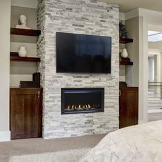 a bedroom with a fireplace and television mounted on the wall