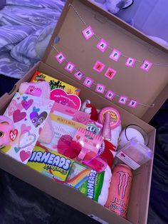 an open box filled with lots of items on top of a purple sheet covered bed