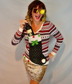 a woman in a christmas sweater and gold sequin skirt holding a bottle of wine