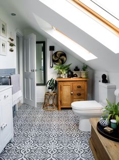 a white toilet sitting next to a wooden cabinet in a bathroom under a skylight