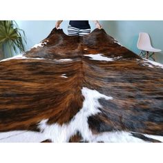 a woman standing on top of a bed covered in brown and white cow hides