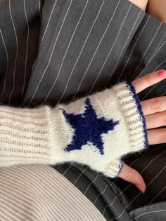 a woman's hand wearing a white and blue knitted mitt with a star on it