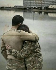 a man and woman hugging in front of a body of water