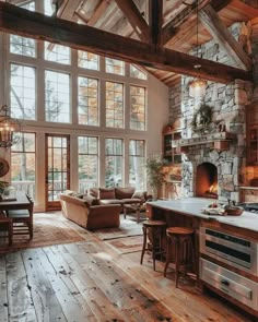 a large open concept kitchen and living room with wood flooring, stone fireplace and high vaulted ceiling