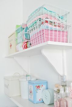 a white shelf with baskets and containers on it