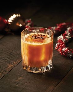 a glass filled with liquid sitting on top of a wooden table next to christmas decorations