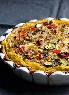 a vegetable quiche in a white dish on a table