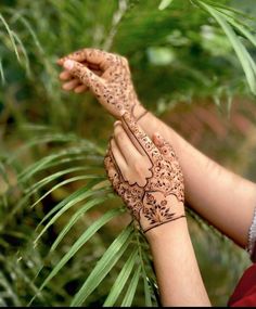 a woman's hands with hennap on her hand and palm trees in the background