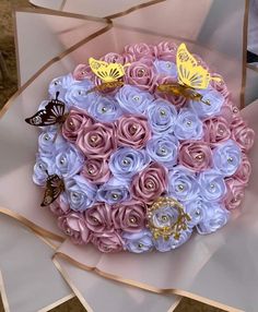 a bouquet made out of pink and blue flowers with butterflies on it, sitting on top of cardboard