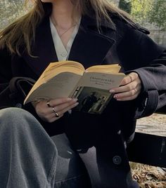 a woman sitting on a bench reading a book