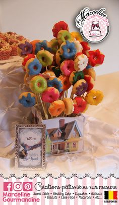 a vase filled with lots of colorful donuts on top of a white table cloth