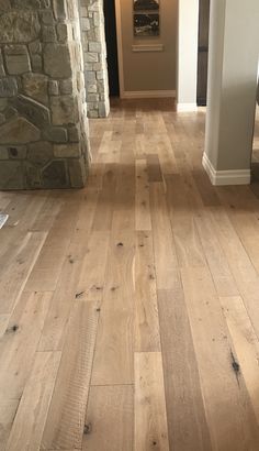 an empty hallway with wood floors and stone walls