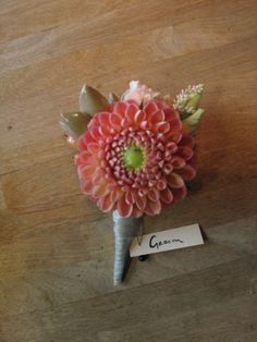 a bouquet of flowers sitting on top of a wooden table next to a name tag