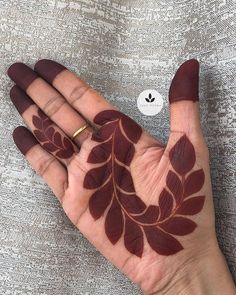 a person's hand painted with brown leaves