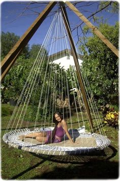 a woman sitting on a hammock in the yard