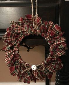 a red and black wreath hanging from the side of a door with a button on it