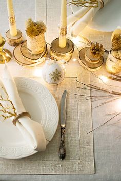 a table set with candles, plates and napkins