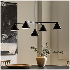 a dining room table with four lights hanging from it's ceiling and a plate on the table