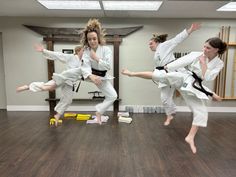 three girls are doing karate moves in a room with hard wood flooring and windows