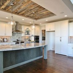 a large kitchen with an island in the middle and wood ceilinging on the walls