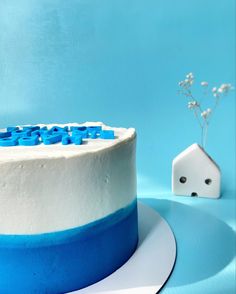 a blue and white cake sitting on top of a table next to a small house