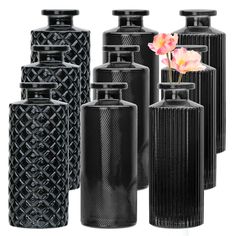 several black vases with flowers in them on a white background and one is empty