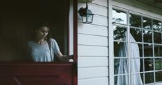 a woman standing in the window of a house