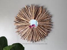 a sunburst made out of sticks is hanging on the wall next to a potted plant