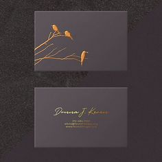 two birds sitting on top of a tree branch in front of a gray business card