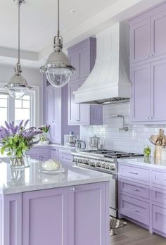 a kitchen with purple cabinets and white counter tops, an island in the middle has flowers on it