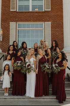 a group of bridesmaids pose for a photo in front of a brick building