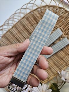 a person holding two blue and white checkered paper clips in their hand next to a wicker basket