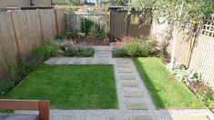 a small garden with grass and stepping stones in the center, next to a wooden fence