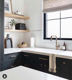 a kitchen with black cabinets, white counter tops and open shelving above the sink