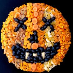 a pumpkin made out of chopped vegetables on top of a black surface