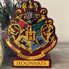 a hogwart's house sign sitting on top of a table next to a potted plant