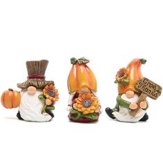 three small figurines with pumpkins and flowers on them, one is holding a sign