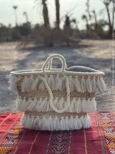 a woven basket sitting on top of a red table cloth next to a palm tree