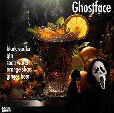 a glass filled with liquid and topped with orange slices next to a ghost face mask