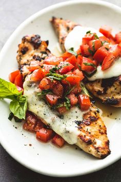 grilled chicken with tomato and basil garnish on a white plate